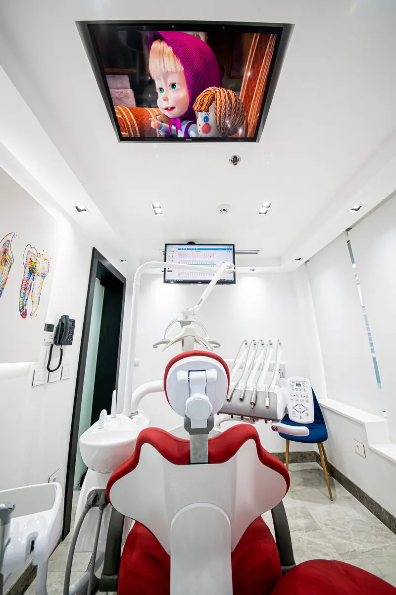 Children’s treatment room with a cartoon playing on a ceiling screen above the dental chair